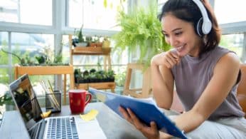 Young female student working from home on her laptop, smiling