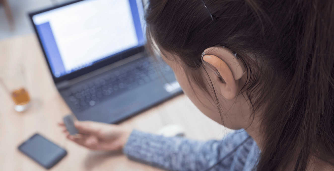 Image of a female student looking at computer wearing a hearing aid.