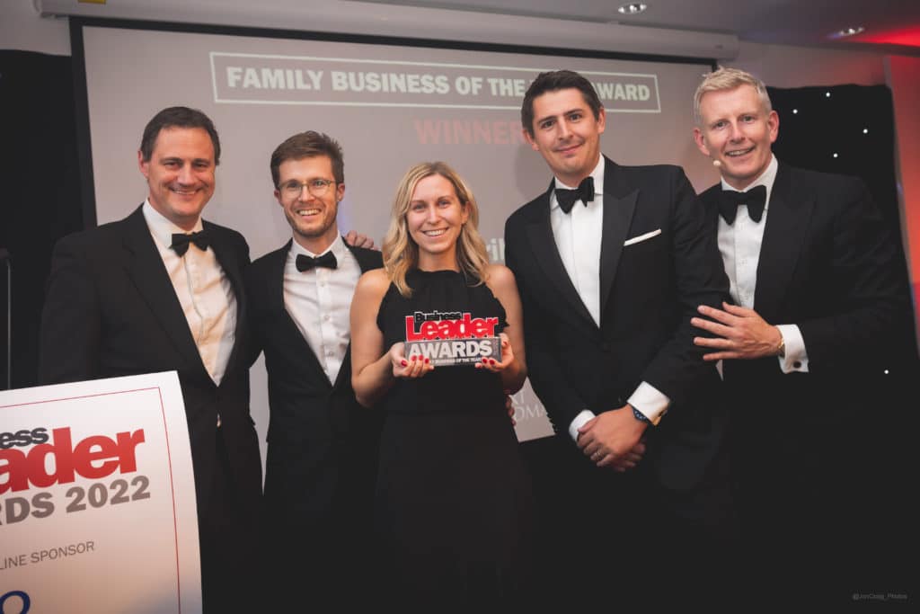 Tom, Claire, and Chris together for a photo at the Business Leader Awards dressed smartly, with Claire holding the award trophy and smiling.