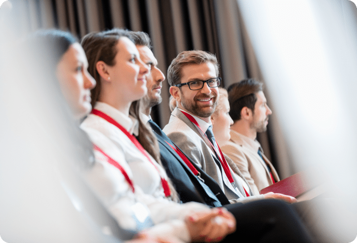 People sat in a row at a conference wearing red lanyards