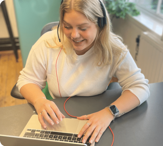 A photo of Elza on a webinar, wearing headphones and a cream top.